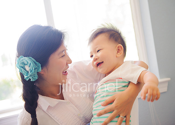 mom and baby play in front of window for their folsom home portraits