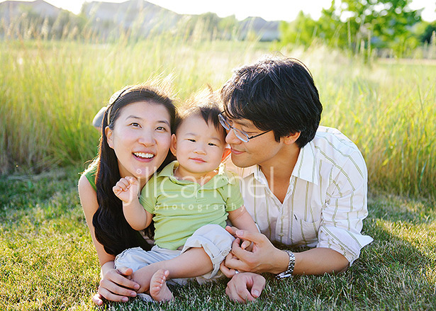 lying on the grass on the golf course for portraits, baby squished between mom and dad 