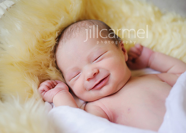 smiling newborn baby face all curled up in sheepskin in sacramento