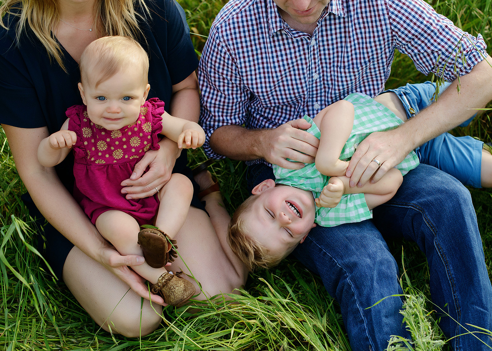 brother and sister tickles and cuddles with mommy and daddy for family photos