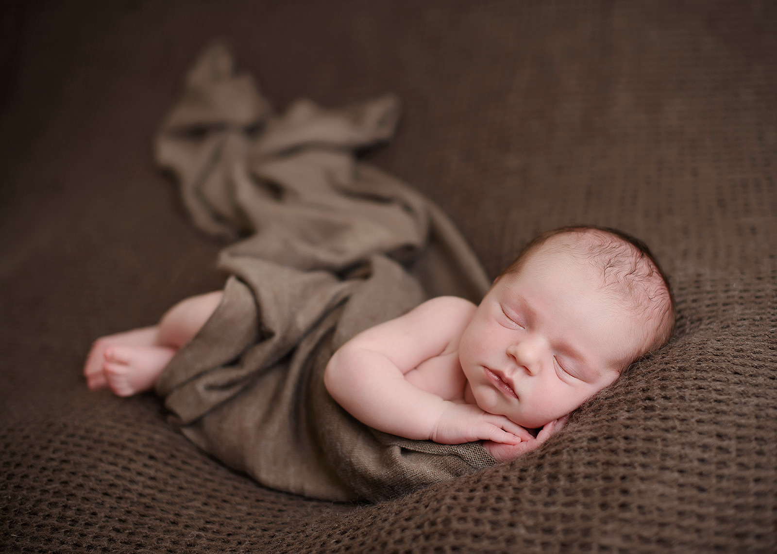 Newborn baby on brown blanket