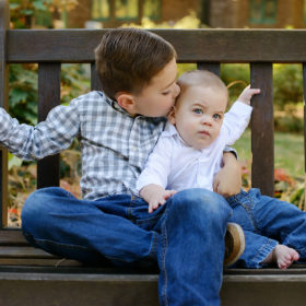 Brothers kissing on bench outdoors