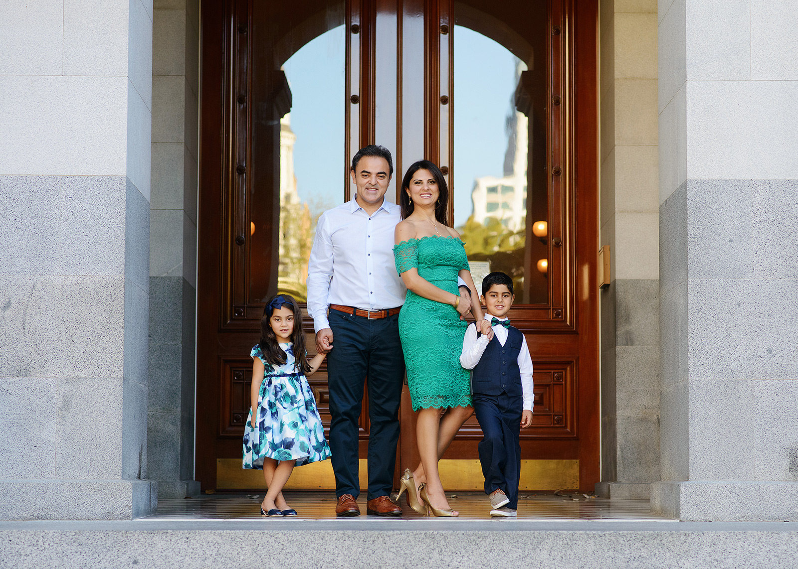 Family posing in front of the doors to the State Capitol