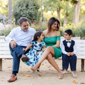 Family sitting on park bench and laughing outdoors