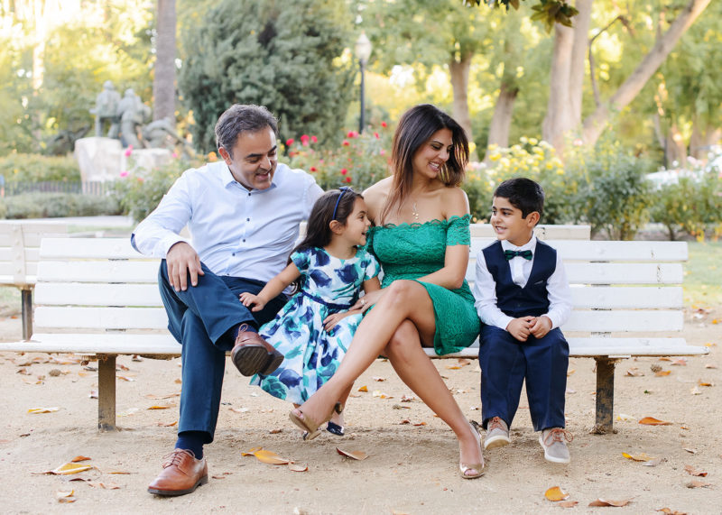 Family sitting on park bench and laughing outdoors