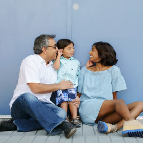 Dad, mom and son smile at each other in front of baby blue door at Folsom Powerhouse