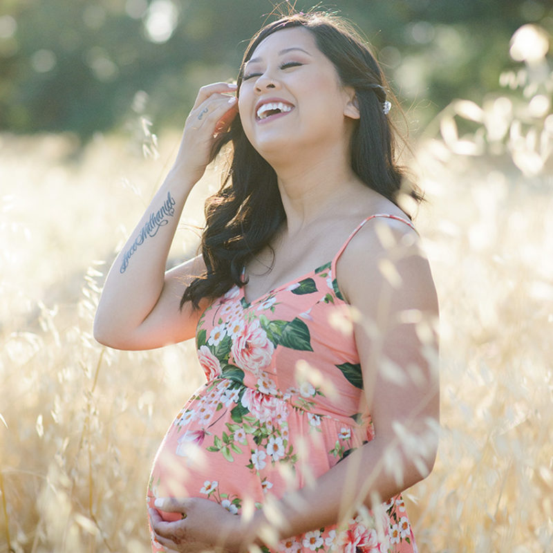 Happy pregnant woman in a field of yellow wheat