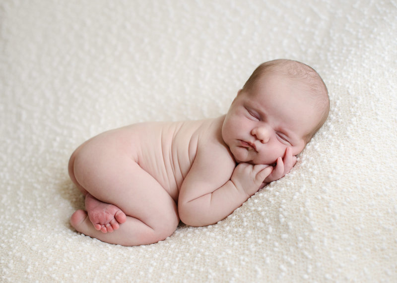 Newborn in Fetal Position Sleeping on Soft White Fleece Blanket