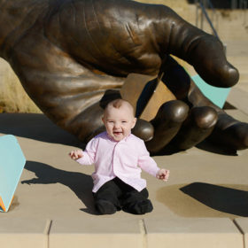 Baby Boy Laughing in Front of Gale Hart Hand Sculpture at Golden 1 Center