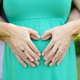 Maternity photos with mom wearing green dress and holding belly with dad