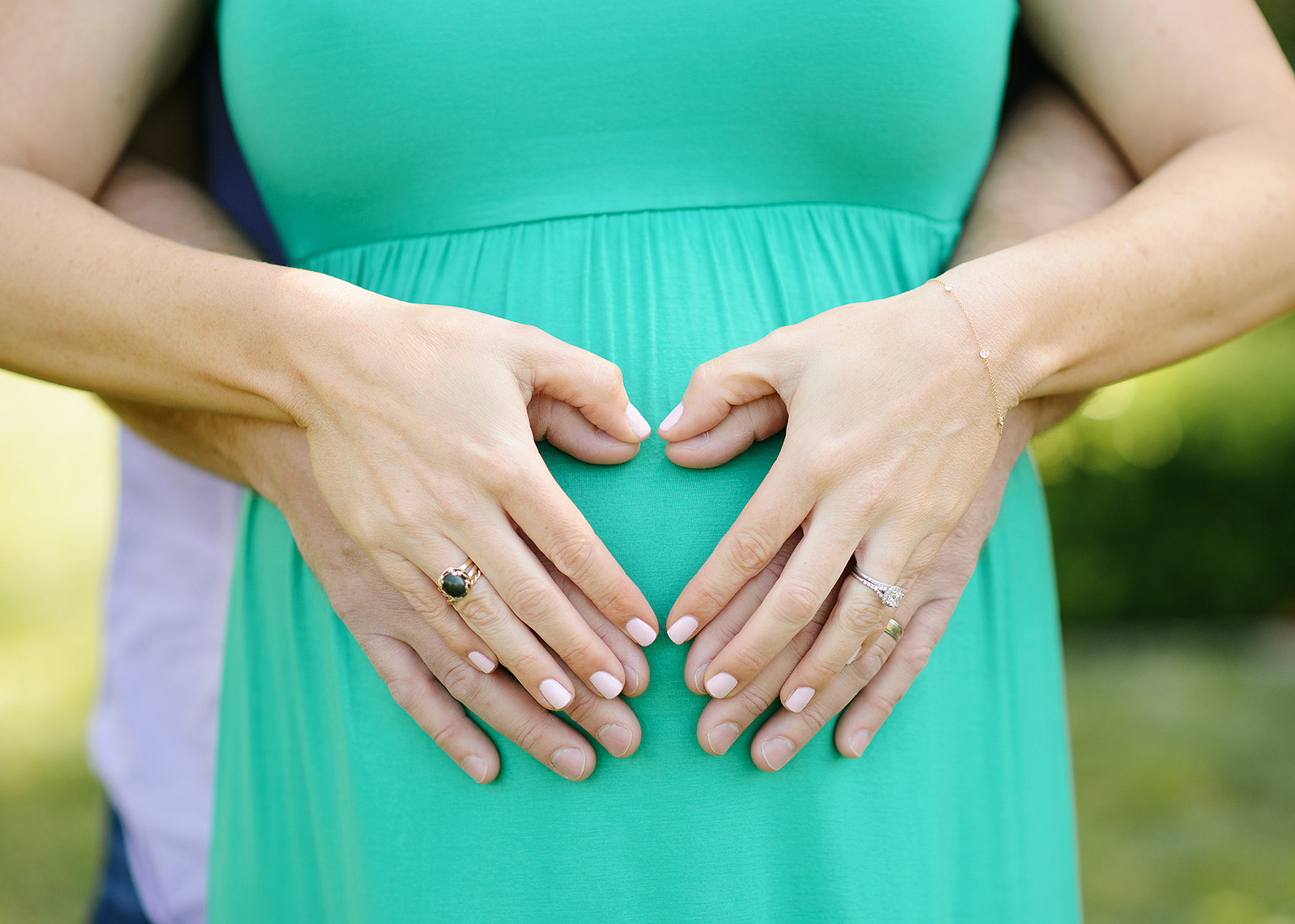 Maternity photos with mom wearing green dress and holding belly with dad