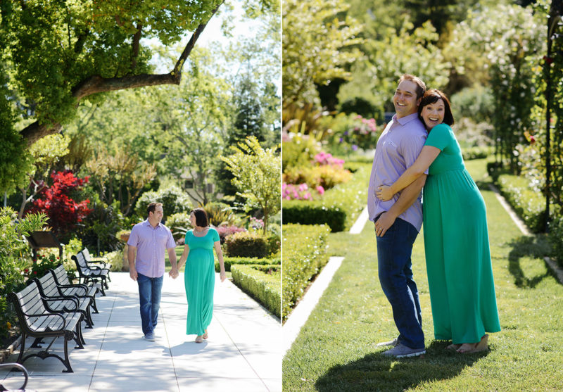 Pregnant couple walking and hugging outside on green lawn and background with trees