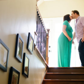 Pregnant couple on top of stairs kissing