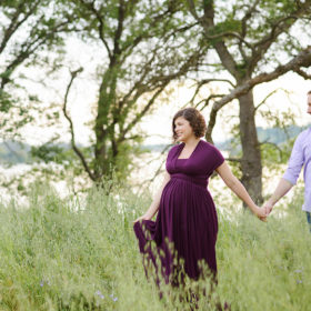 Maternity photos with husband holding hands in green grassy field Folsom