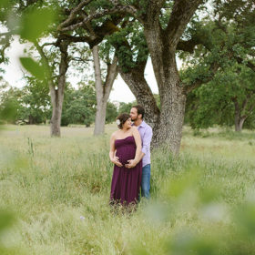 Pregnant couple hugging under trees outdoors in Folsom