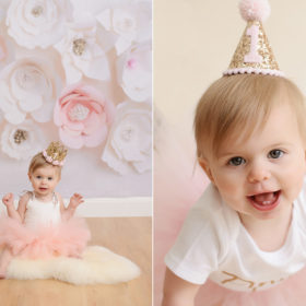 One year old baby girl in pink tutu smiling against paper flowers