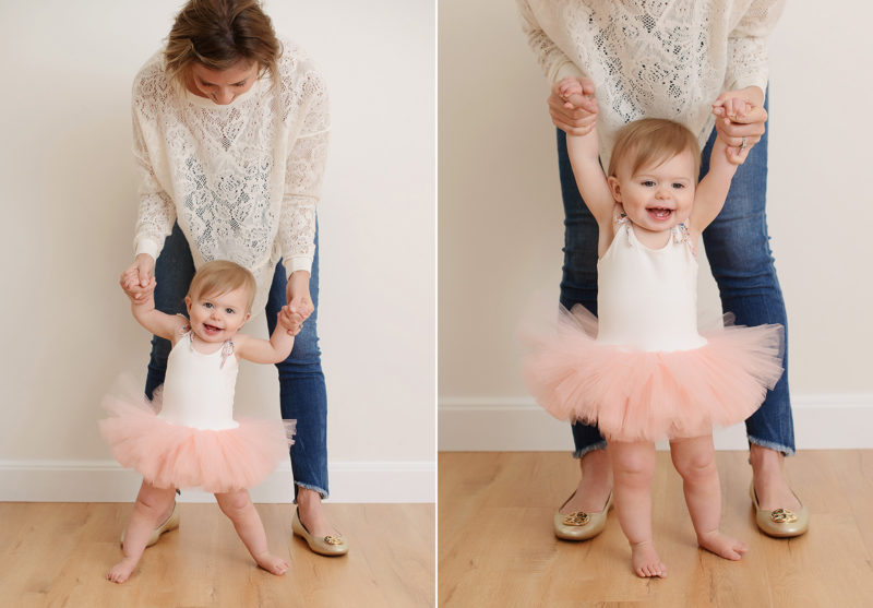 Mom holding baby girl in tutu up to standing