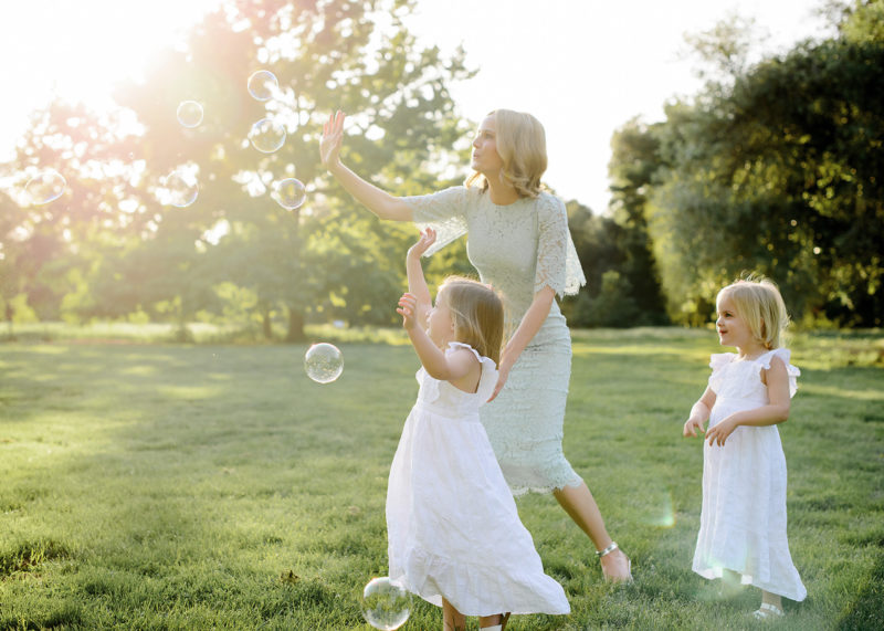 Mom and daughters blowing bubbles outdoors in Sacramento