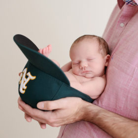 Dad holding newborn baby girl in Oakland As cap