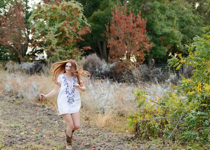 Senior Girl Running in Cowboy Boots and Tunic in Outdoor Field Foliage