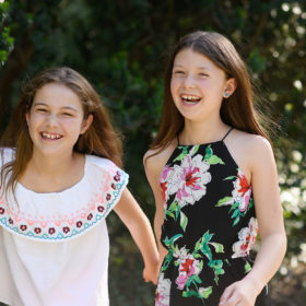 Sisters wearing floral print outdoors with trees in background