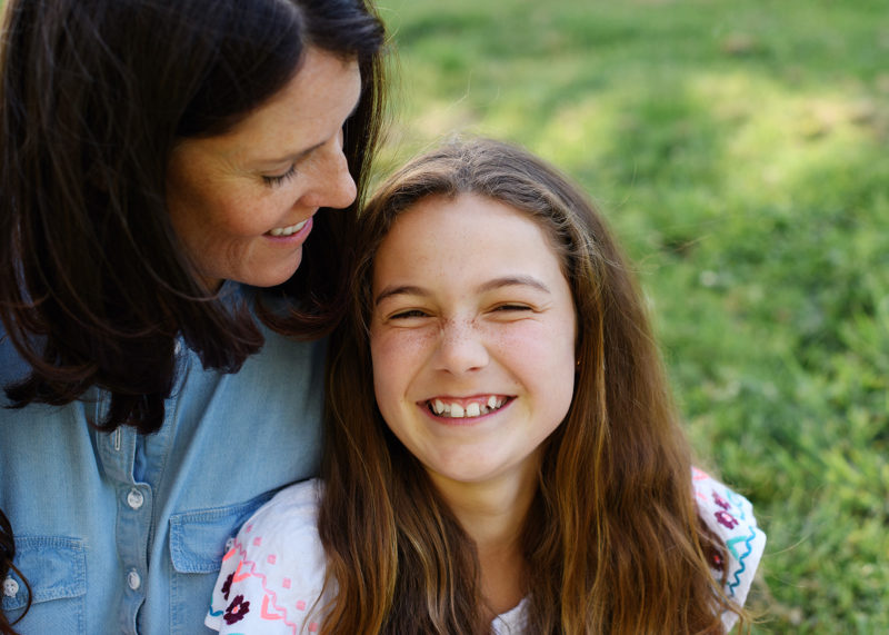 Mom and daughter laughing and smiling sitting on grass in Sacramento