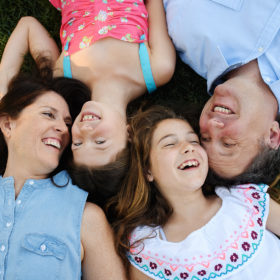 Family smiling and lying on grass outside