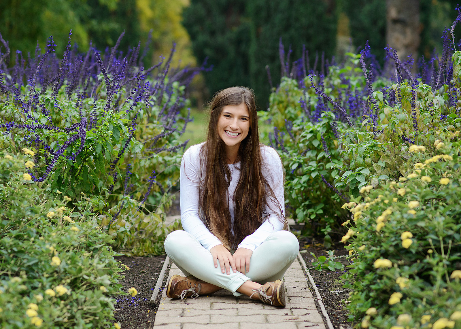 brunette teen portrait sitting down in wildflower garden in Sacramento