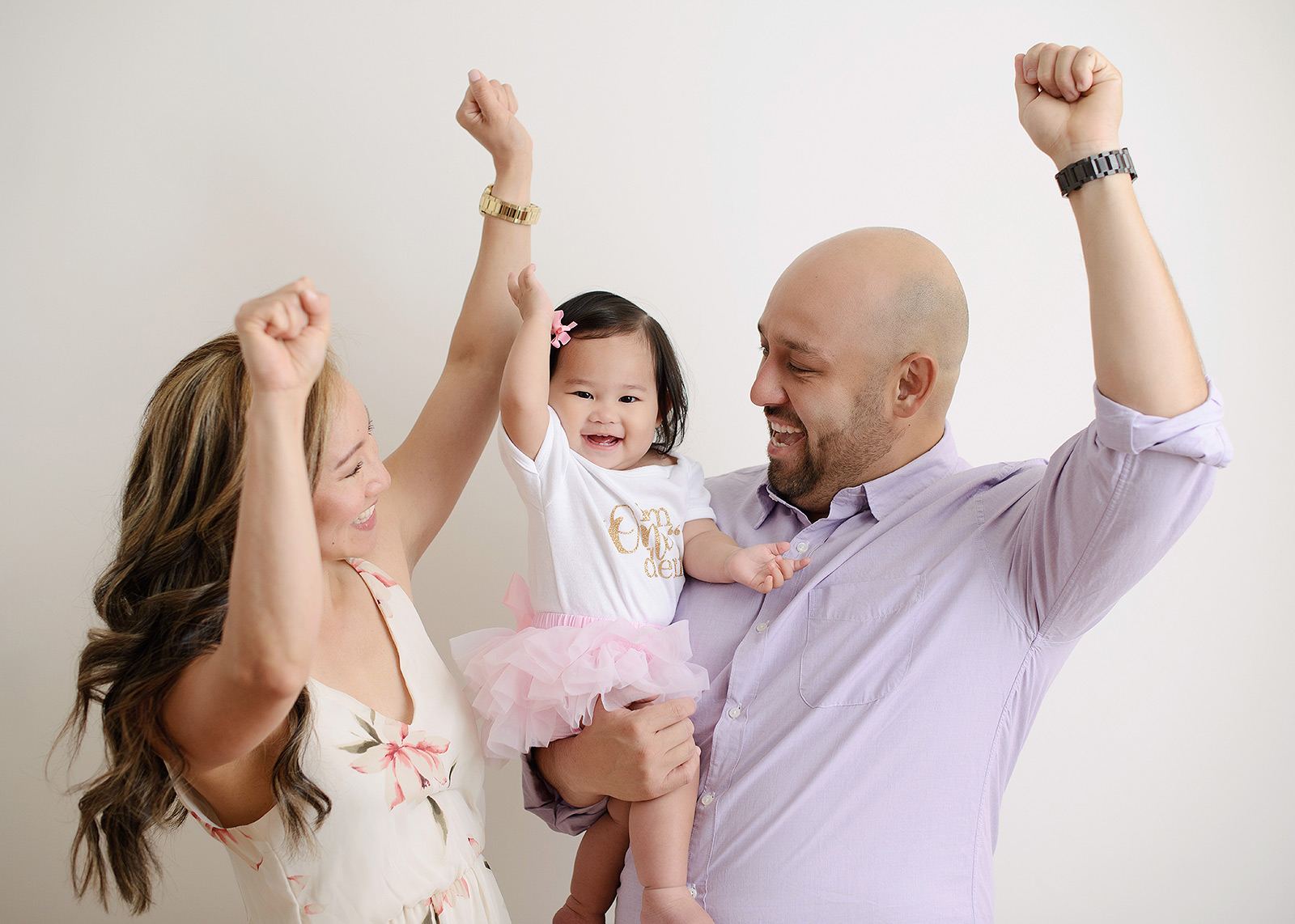 Family putting fists up to celebrate one year old baby girl's birthday