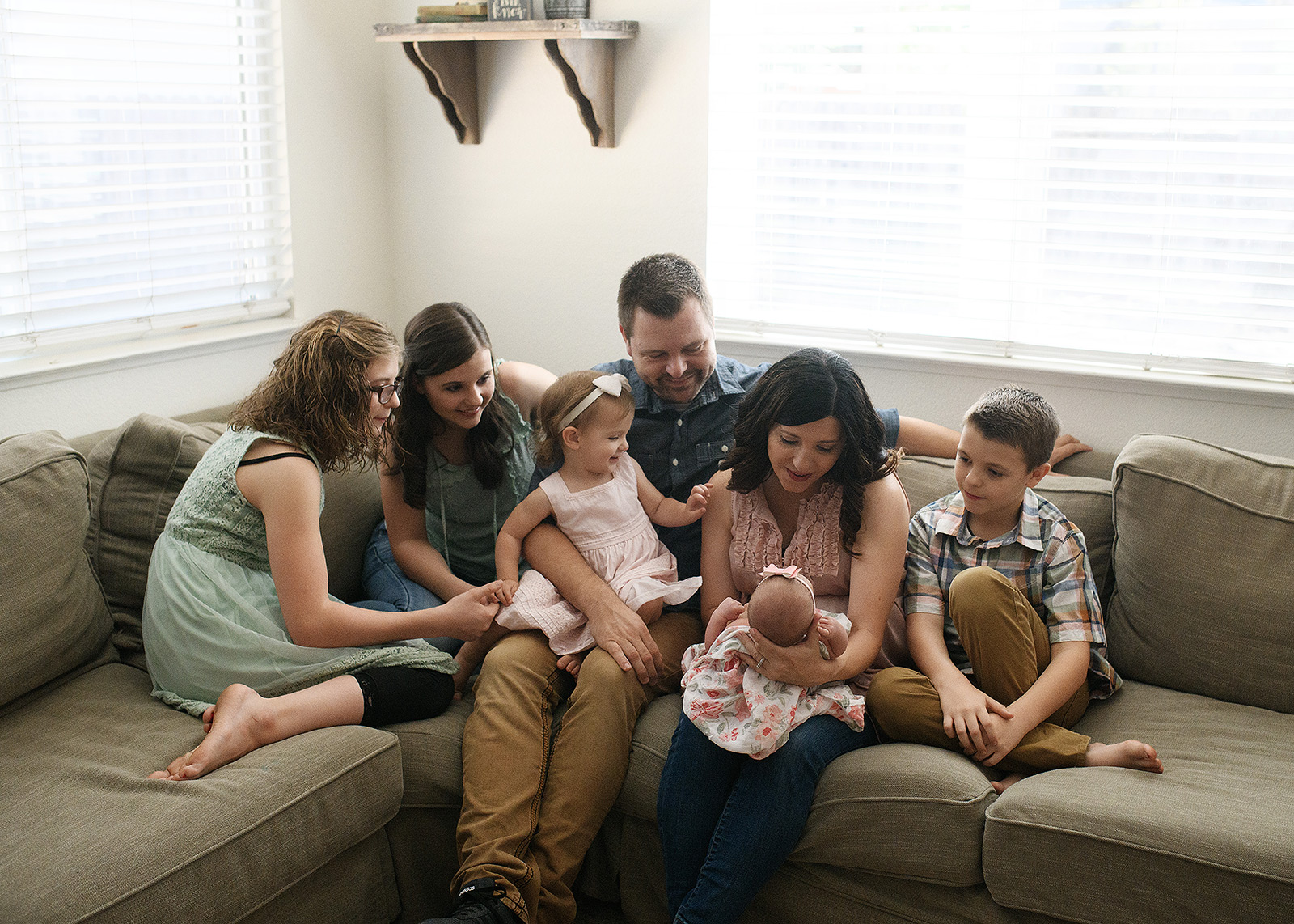 Lifestyle family photo with newborn baby girl on couch in home
