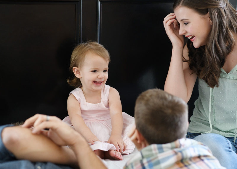 Big sister laughing with other siblings on bed family photo