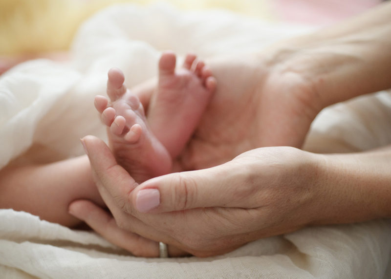 Mom holding newborn baby girl feet