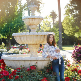 Senior girl posing by fountain and red flowers at State Capitol