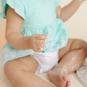 Frosting on baby girl’s legs and feet during cake smash