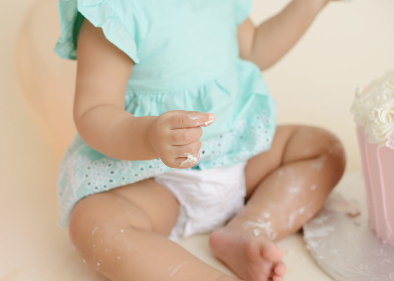 Frosting on baby girl's legs and feet during cake smash