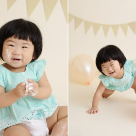 Baby girl laughing and playing with balloons and frosting during cake smash