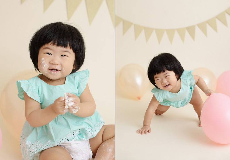 Baby girl laughing and playing with balloons and frosting during cake smash