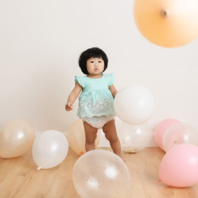 Baby girl in a sea of pastel balloons