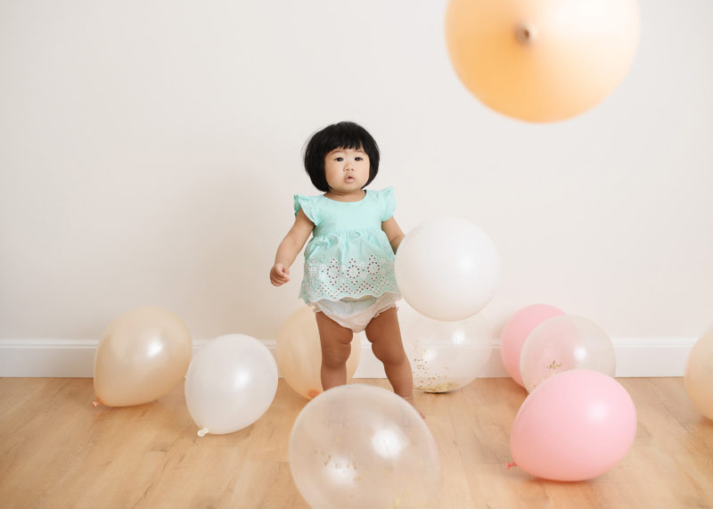 Baby girl in a sea of pastel balloons