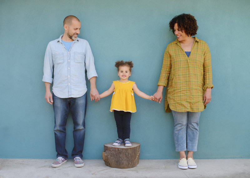 Mixed race family photo outside home with blue wall background in Sacramento