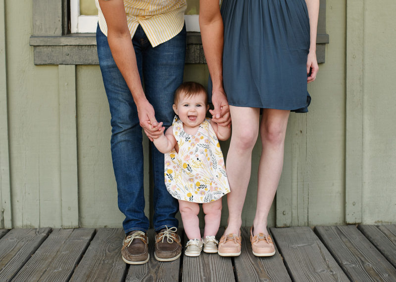 Baby girl standing up next to mom and dad wearing matching boat shoes in Old Sacramento