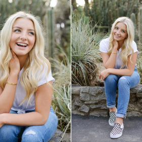 Senior portrait of blonde girl in jeans and sneakers sitting down at State Capitol outdoors
