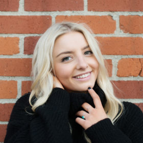 Senior portrait of teen girl smiling against brick wall background in State Capitol