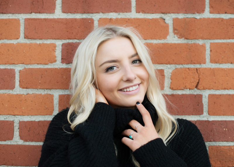 Senior portrait of teen girl smiling against brick wall background in State Capitol