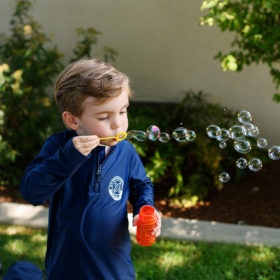 Boy blows bubbles during first birthday party outside