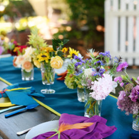 First birthday party tablescape with bright floral arrangements and napkins