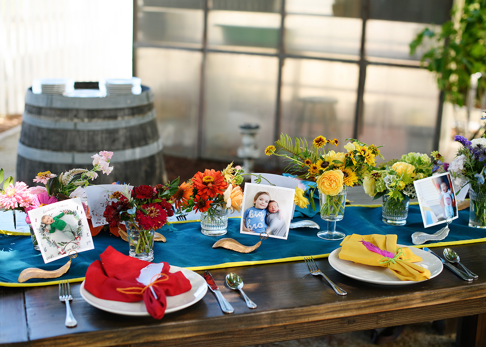 First birthday party tablescape with photos and multicolor florals and feathers