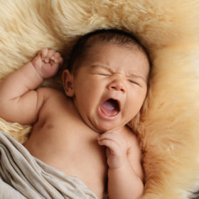 Newborn baby yawns on fuzzy throw blanket