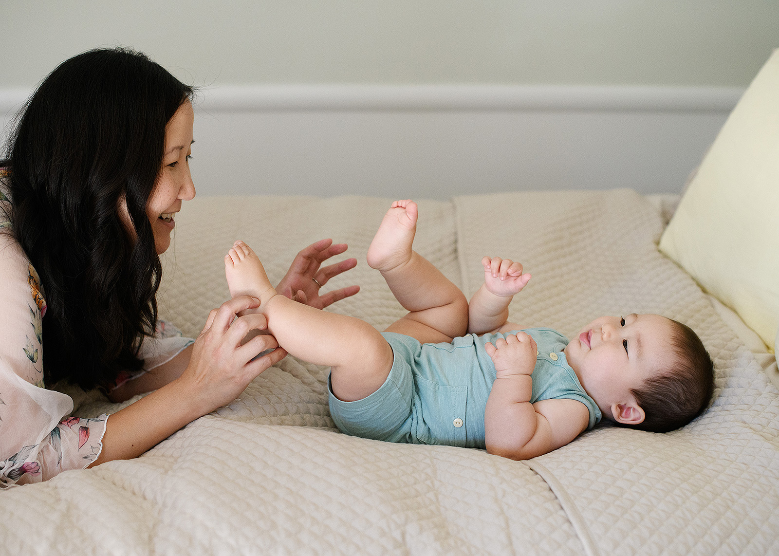 Mom plays with 6 month baby boy on bed lifestyle session