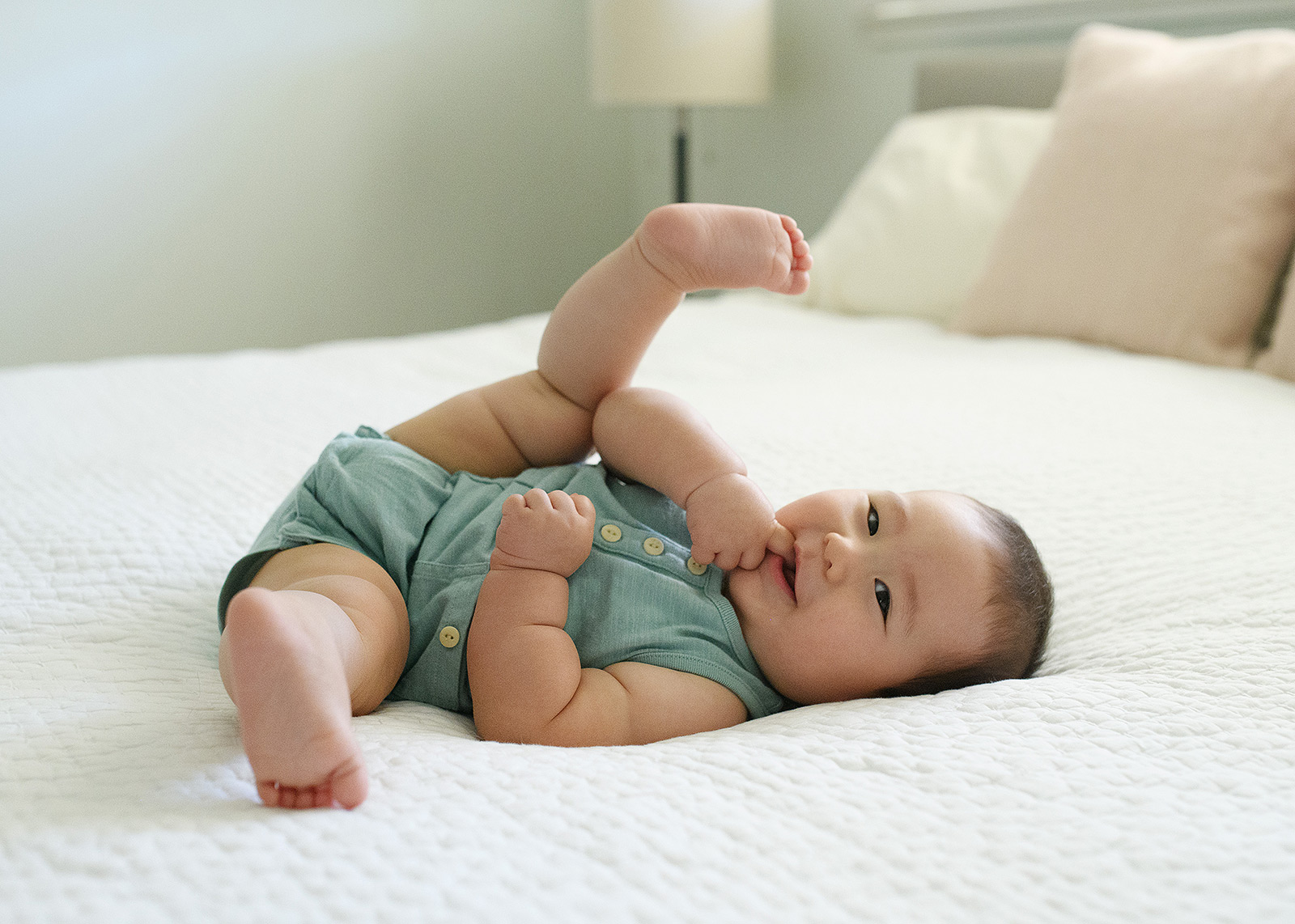 6 month old baby boy feeling coy on bed with natural light lifestyle session